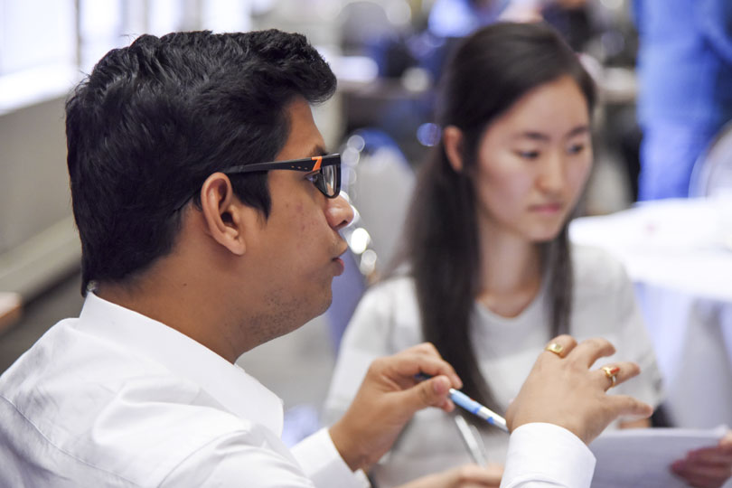 A man gestures with his hands as he talks while a woman listens
