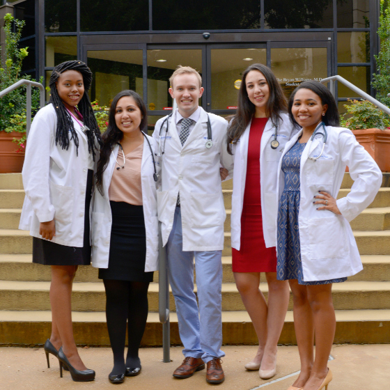 Four female medical students and a male medical student stand in front of a building on the UT Southwestern campus