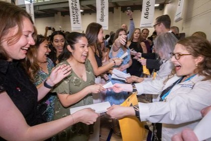 crowd of female medical students cheer and gather together to receive their match day envelopes